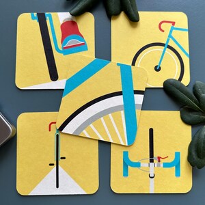 Könnte beinhalten: Satz von fünf gelben Untersetzern mit schwarz-weißen Fahrrad-Illustrationen. Jeder Untersetzer zeigt ein anderes Detail eines Fahrrads, einschließlich Lenker, Räder und Pedale.