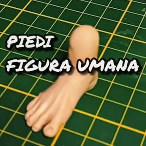 Può includere: Una scultura dettagliata di un piede color beige con dita visibili e una consistenza liscia. Il testo "PIEDI FIGURA UMANA" è visualizzato in bianco, bordato di nero. Il piede è posizionato su una superficie verde con un motivo a griglia.