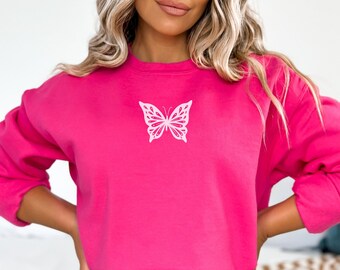 May include: A pink sweatshirt with a white butterfly graphic on the front. The sweatshirt is cropped and has long sleeves.