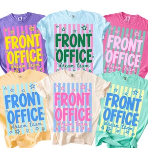 K&ouml;nnte beinhalten: Sechs kurz&auml;rmelige T-Shirts in Lila, Hellblau, Pink, Gelb, Creme und Mintgr&uuml;n. Jedes T-Shirt zeigt eine zentrale Grafik mit vertikalen Streifen, dem Text "FRONT OFFICE" in gro&szlig;en Blockbuchstaben und "dream team" in Schreibschrift.