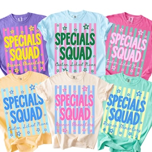 May include: Six short-sleeved t-shirts in purple, light blue, pink, yellow, cream, and mint green. Each shirt features a central rectangular graphic with vertical stripes, star accents, and the text "SPECIALS SQUAD" with "Keenan Elementary" or "Custom School Name" below.