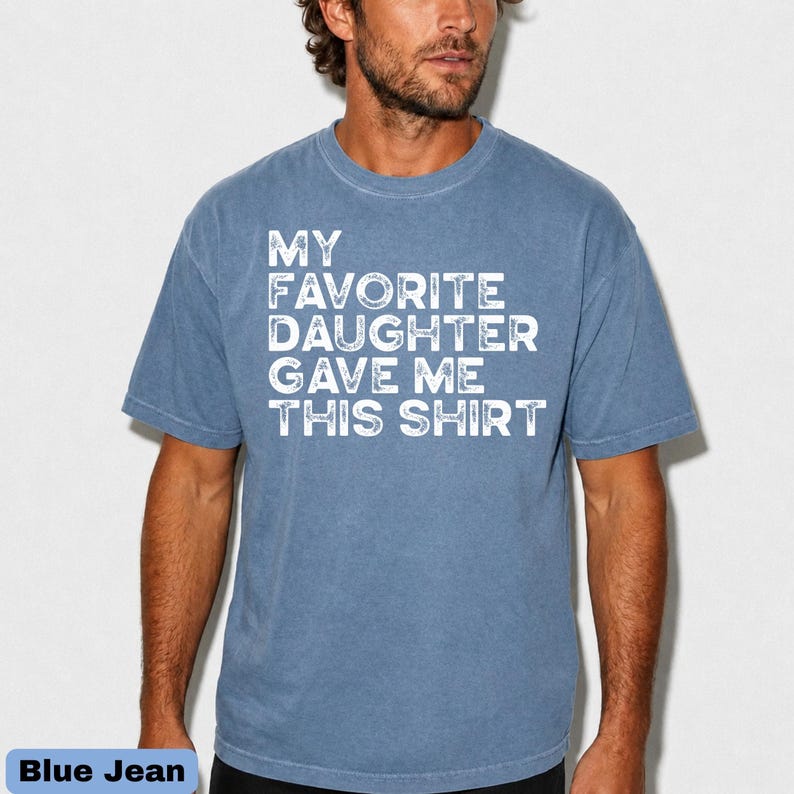 Pu&ograve; includere: T-shirt blu jeans con la scritta "MY FAVORITE DAUGHTER GAVE ME THIS SHIRT" in lettere bianche. La maglietta &egrave; a girocollo e ha maniche corte.