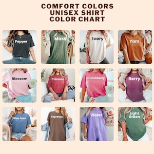 K&ouml;nnte beinhalten: Eine Comfort Colors Unisex-T-Shirt-Farbkarte mit zw&ouml;lf kurz&auml;rmeligen T-Shirts in verschiedenen Farben, beschriftet mit Pepper, Moss, Ivory, Yam, Blossom, Crimson, Crunchberry, Berry, Blue Jean, Espresso, Violet und Light Green auf hellem Grund.