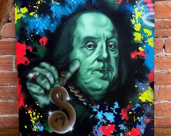 May include: A canvas art piece featuring a portrait of Benjamin Franklin in shades of green, holding a dollar sign pendant. The background is black with colorful paint splatters in red, blue, and yellow.