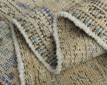 May include: Close-up of a woven rug with a beige background and stripes of brown, blue, and green.
