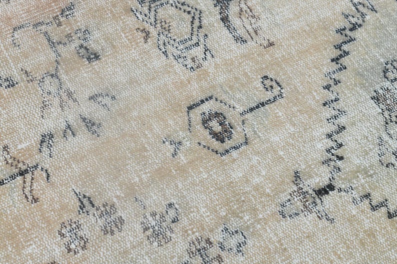 May include: A woven rug featuring a light beige background with a repeating pattern of dark grey geometric shapes, including stylised hexagonal motifs and jagged lines, creating a textured surface with a distressed appearance.