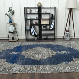 May include: A vintage blue and cream rug with a floral pattern. The rug has a distressed look and is perfect for adding a touch of bohemian style to any room.