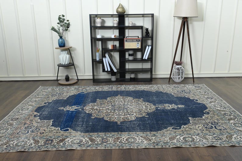 May include: A vintage blue and cream rug with a floral pattern. The rug has a distressed look and is perfect for adding a touch of bohemian style to any room.