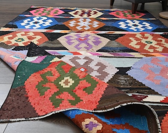 May include: A colourful handwoven rug with a geometric pattern in shades of red, blue, green, and brown. The rug is folded in half, revealing the intricate details of the design.