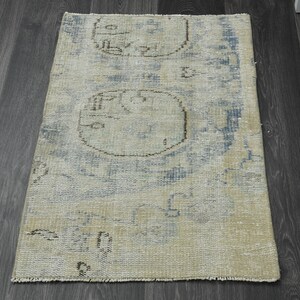 May include: A light blue and beige rug with a distressed look. The rug has a geometric pattern with circles and lines.