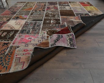 May include: A colorful patchwork rug with a variety of patterns and colors, including red, blue, green, and brown. The rug is made of different fabrics and is hand-woven. The rug is folded in half and the underside is visible.