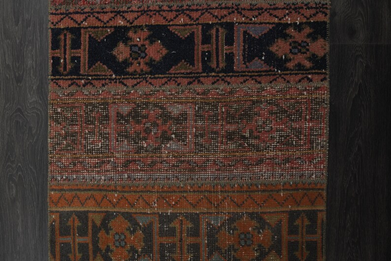 May include: A vintage rug with a geometric pattern in shades of red, brown, and black. The rug has a worn and faded look, giving it a rustic and antique feel.