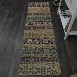May include: A long, narrow rug with a colourful, geometric pattern. The rug has a faded, vintage look and is made of a soft, woven material. The rug is perfect for adding a touch of bohemian style to any room.