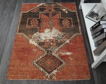 May include: A vintage red and black rug with a geometric pattern. The rug has a worn and faded look, giving it a rustic and antique feel.