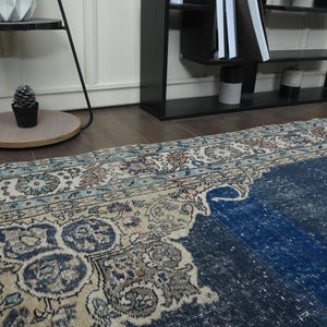 May include: A vintage rug with a faded blue and cream color scheme. The rug has a traditional Persian design with intricate floral patterns.
