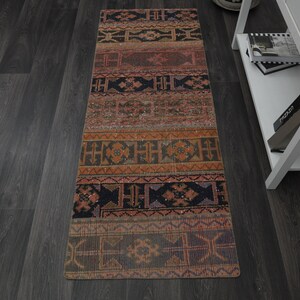 May include: A long, narrow rug with a colourful geometric pattern in shades of red, orange, brown, and black. The rug has a traditional, ethnic design.