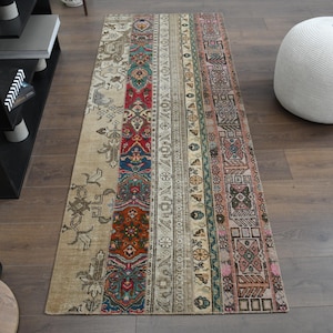 Può includere: Un tappeto lungo e rettangolare con sfondo crema e motivi geometrici colorati. Il tappeto ha un aspetto sbiadito e vintage ed è fatto di tessuto tessuto.