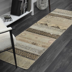May include: A beige and brown striped runner rug with a geometric pattern. The rug is on a dark wood floor.