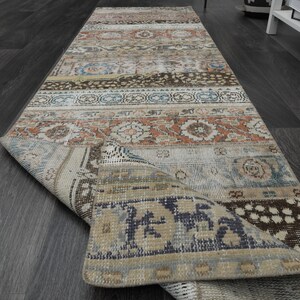 May include: A vintage style runner rug with a faded, multi-coloured pattern. The rug has a distressed look with a mix of blues, browns, and creams.