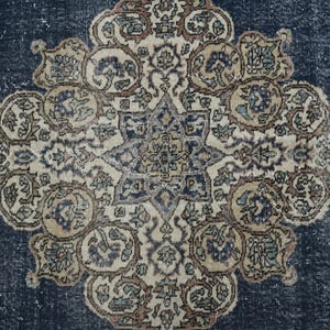 May include: A vintage rug with a blue background and a central medallion with intricate floral patterns in shades of beige, brown, and white.