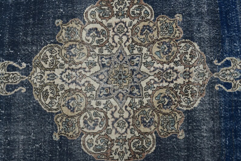 May include: A vintage rug with a blue background and a central medallion with intricate floral patterns in shades of beige, brown, and white.