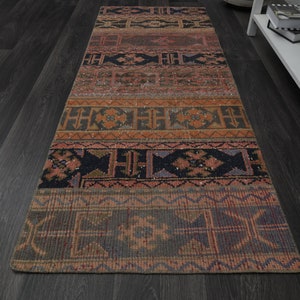May include: A long, narrow rug with a colourful, geometric pattern. The rug has a dark background with shades of red, orange, and blue. The pattern is made up of repeating shapes and lines.