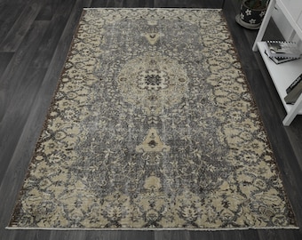 May include: A vintage-style rug with a faded floral pattern in shades of brown, beige, and gray. The rug has a distressed look and a worn texture.