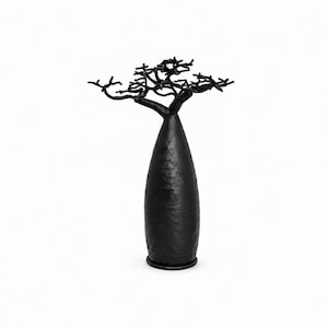 May include: A matte black sculpture shaped like a baobab tree with a thick, textured, cylindrical trunk and a wide, intricate canopy of thin, sprawling branches. The object stands upright on a flat, circular base against a plain white background.