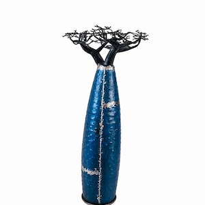 Peut inclure: Une sculpture en forme de baobab avec un tronc bleu texturé, cylindrique et haut, présentant des coutures argentées verticales et horizontales. Le sommet de la sculpture se compose de fines branches sombres qui s'étendent vers l'extérieur.