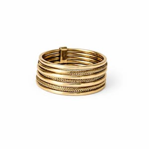Op de afbeelding: Een goudkleurige ring met meerdere banden. De ring heeft een textuurontwerp op sommige banden. De ring staat tegen een witte achtergrond. De ring lijkt van metaal te zijn.