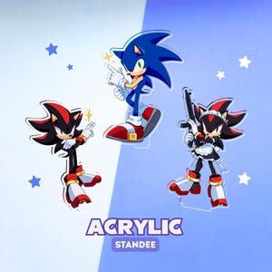 Op de afbeelding: Drie acryl standaards met stripfiguren: een blauwe egel die wijst, een zwart-rode egel in pose, en een zwart-rode egel in een dienstmeisjesoutfit met een geweer. De tekst ACRYLIC STANDEE staat onderaan afgebeeld.