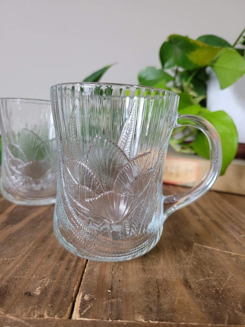 Puede incluir: Dos tazas de vidrio transparente con un dise&ntilde;o floral. Las tazas tienen un asa y est&aacute;n hechas de vidrio grueso.