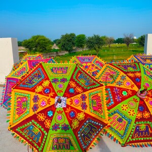 以下が含まれることがあります： 鮮やかな刺繍模様が施された、カラフルな装飾用傘のコレクション。赤、緑、黄色、ピンクなどの鮮やかな色合いで、花柄や象のモチーフなど、細部までこだわったデザインが特徴です。各傘にはタッセルが付いています。