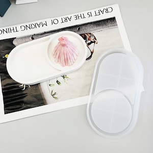 Puede incluir: Dos moldes de silicona blanca para fundición de resina. Un molde es de forma ovalada con una hendidura redonda, el otro es de forma ovalada con una hendidura redonda y una hendidura redonda más pequeña en el interior.