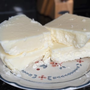 May include: A stack of four white, rectangular blocks of cheese on a white plate with a blue and red floral pattern.