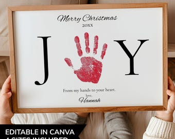 May include: A wooden framed print featuring a red handprint on a white background. The word "JOY" is spelled out in black. The text reads "Merry Christmas 20XX" and "From my hands to your heart, love, Hannah".