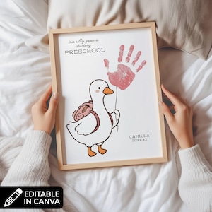 May include: A framed print featuring a white goose illustration with an orange beak and feet, wearing a pink backpack. Above the goose, the text reads this silly goose is starting PRESCHOOL. A red handprint balloon is held by the goose, with CAMILLA 20XX-XX printed below.