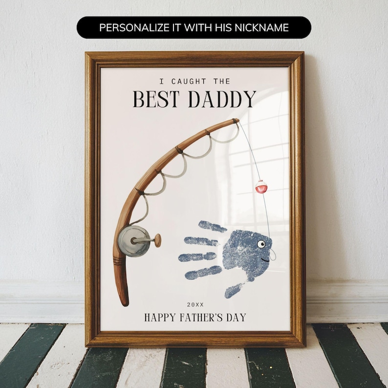 May include: A framed wall art print featuring a brown fishing rod and a blue handprint shaped like a fish. The text reads I CAUGHT THE BEST DADDY, 20XX, and HAPPY FATHER'S DAY. The design includes a fishing line with a small red and white bobber.