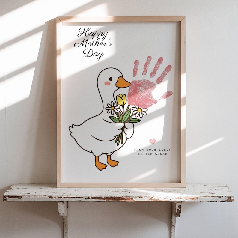 May include: A framed print for Mother's Day featuring a cartoon goose holding flowers. The print includes a pink handprint and the text "Happy Mother's Day" and "From Your Silly Little Goose."