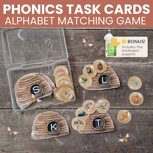 May include: Phonics task cards alphabet matching game featuring beehive-shaped cards with letters S, K, and T, and circular cards with illustrations. Includes a clear plastic storage case and a bonus card with text: BONUS! Includes free beekeeper puppets.