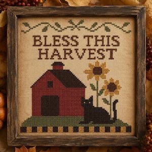 May include: A framed cross-stitch sampler on tan fabric featuring the text BLESS THIS HARVEST in brown. The design includes a red barn, two yellow sunflowers, and a black cat sitting on a green hill with a black and yellow chequered border.