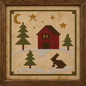 May include: A framed cross-stitch embroidery on tan fabric featuring a red house with a brown roof, three green pine trees, a brown rabbit, and a yellow crescent moon with stars, all set against a snowy landscape with a green border.
