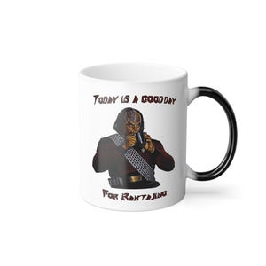 May include: White ceramic mug with a black handle featuring a Star Trek design. The mug has an image of a character drinking from a mug, with the text "TODAY IS A GOOD DAY FOR RAKTAJINO" in brown lettering.
