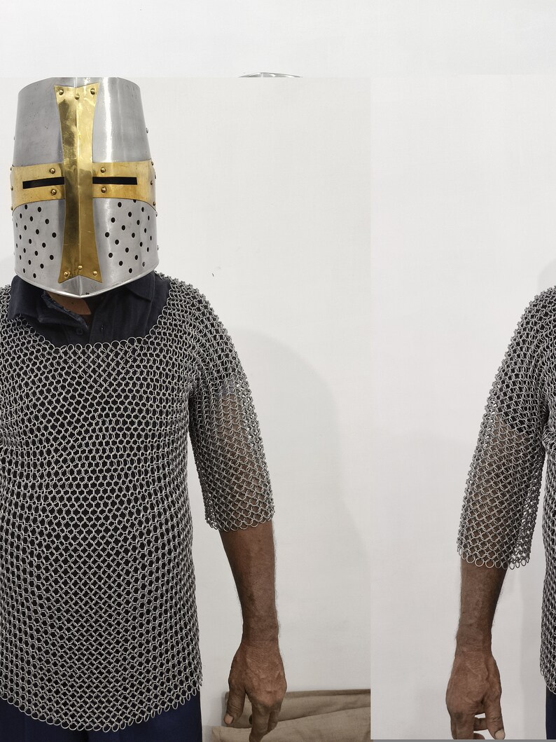 May include: A silver chainmail shirt with a short sleeve design. The shirt is worn by a person wearing a silver helmet with a gold cross.