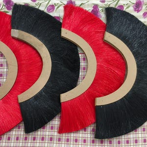 Peut inclure: Quatre brosses en demi-cercle avec des poils noirs et rouges. Les brosses sont fixées à des cadres en bois.