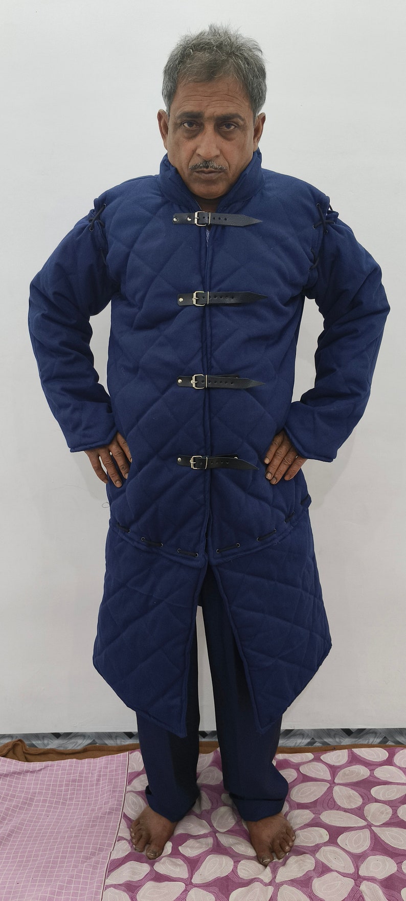 May include: A blue quilted jacket with a long length and multiple buckles. The jacket is made of a thick, durable fabric and has a classic design.