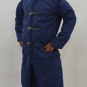May include: A blue quilted jacket with a high collar and multiple buckles. The jacket has a diamond pattern and is lined with a soft material.