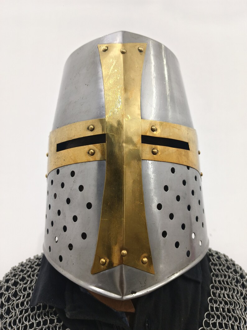 May include: A silver helmet with a gold cross design and a perforated metal surface. The helmet is a traditional crusader helmet.