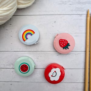 Puede incluir: Cuatro cintas m&eacute;tricas retr&aacute;ctiles de colores con diferentes dise&ntilde;os. Un arco&iacute;ris, una fresa, una sand&iacute;a y una nube con una cara sonriente.