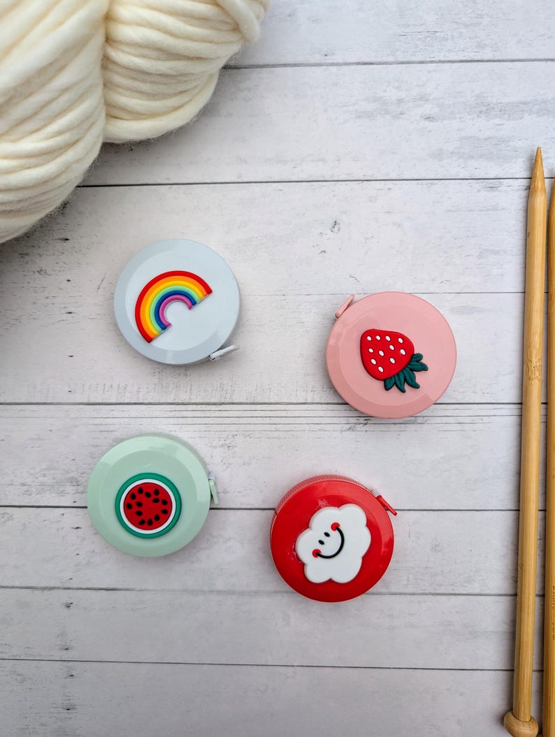 Puede incluir: Cuatro cintas m&eacute;tricas retr&aacute;ctiles de colores con diferentes dise&ntilde;os. Un arco&iacute;ris, una fresa, una sand&iacute;a y una nube con una cara sonriente.